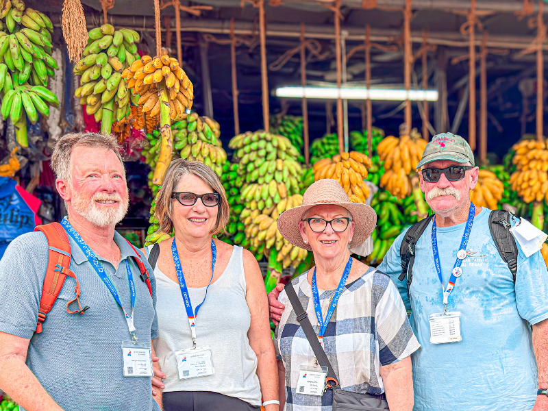 Tour group standing in front of a massive bunch of bananas at a local market, Sri Lanka food tours