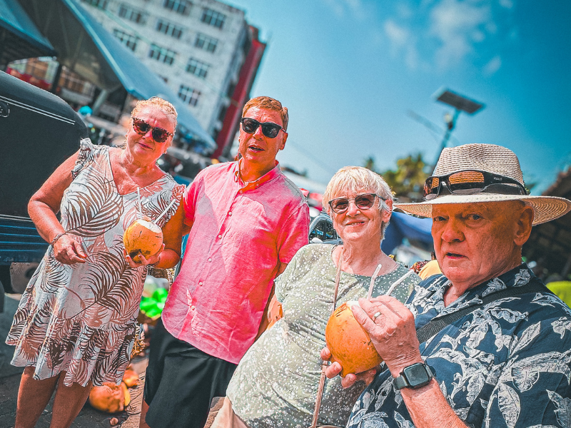 Happy tourists enjoying fresh king coconuts on Colombo food tour itinerary with local guide in Sri Lanka