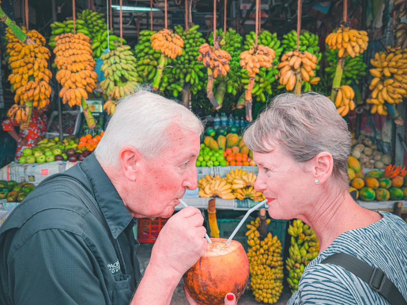 Lovely Old Couple sampling fresh tropical fruits at local market during Sri Lanka food tour experience