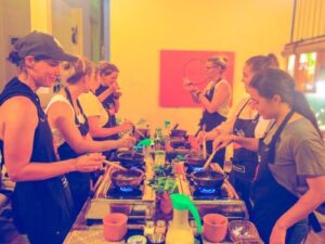 A large group of female travelers (10)enjoying a Sri Lanka cooking class by Rustic, tasting curry from clay pots while cooking to check if the flavors are perfect.