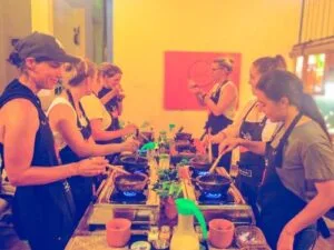 A large group of female travelers (10)enjoying a Sri Lanka cooking class by Rustic, tasting curry from clay pots while cooking to check if the flavors are perfect.