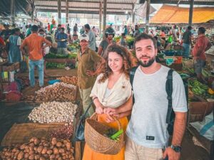 A honeymoon couple picking fresh ingredients with a cane basket at a local Colombo market before their Colombo Cooking Class by Rustic.